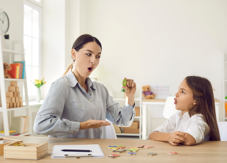 A female physical therapist assisting a male patient with leg exercises in a well-lit clinic.